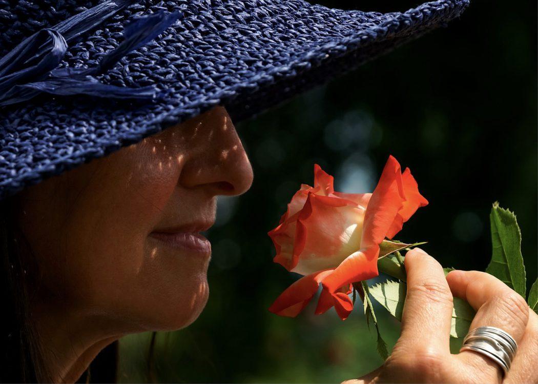 kobieta w kapeluszu z pierścionkiem na palcu i różą w dłoni