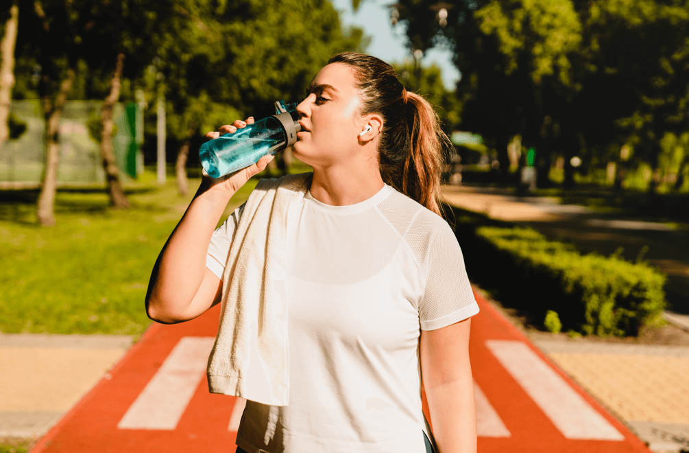 lekko otyła kobieta pijąca wodę w letni dzień