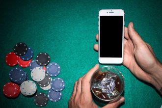 smartfon w dłoni i żetony w kasynie
