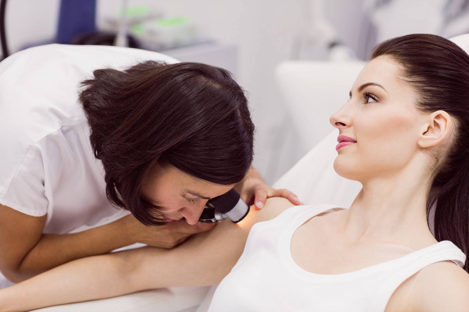 dermatologist examining skin patient with dermatoscope wp