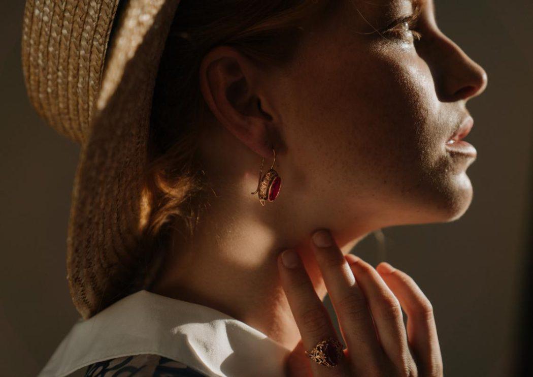kolczyki wiszące na uchu kobiety w kapeluszu słomkowym