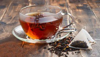 Glass transparent cup of black tea and dry tea in bags on the ba