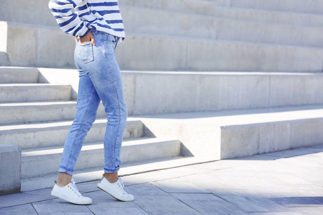 Young hipster woman in stylish jeans standing near stairs outdoo