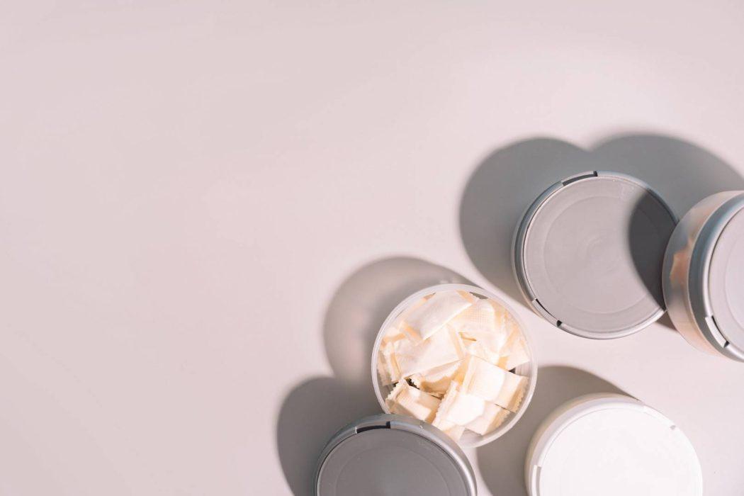 Plastic jars with snus bags under hard light top view