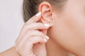 Ear piercing. Cropped shot of a young woman wearing elegant stud