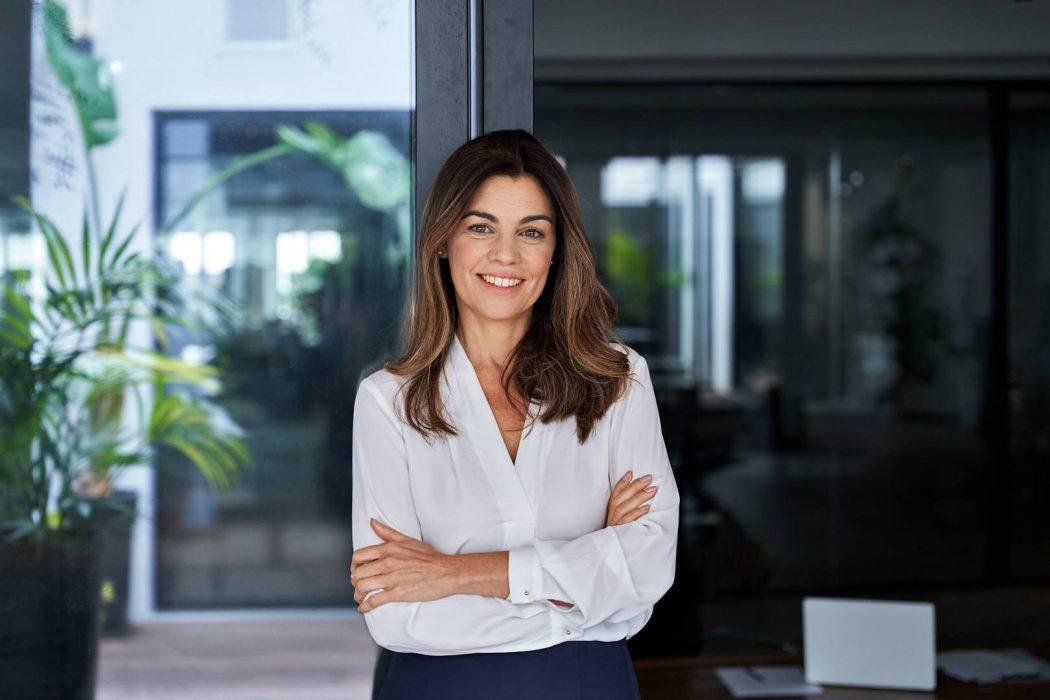 Happy elegant older mature lady posing for portrait standing at work in office.