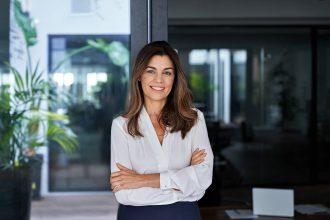 Happy elegant older mature lady posing for portrait standing at work in office.