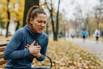 Young caucasian woman experiencing chest pain in autumn park setting for health awareness