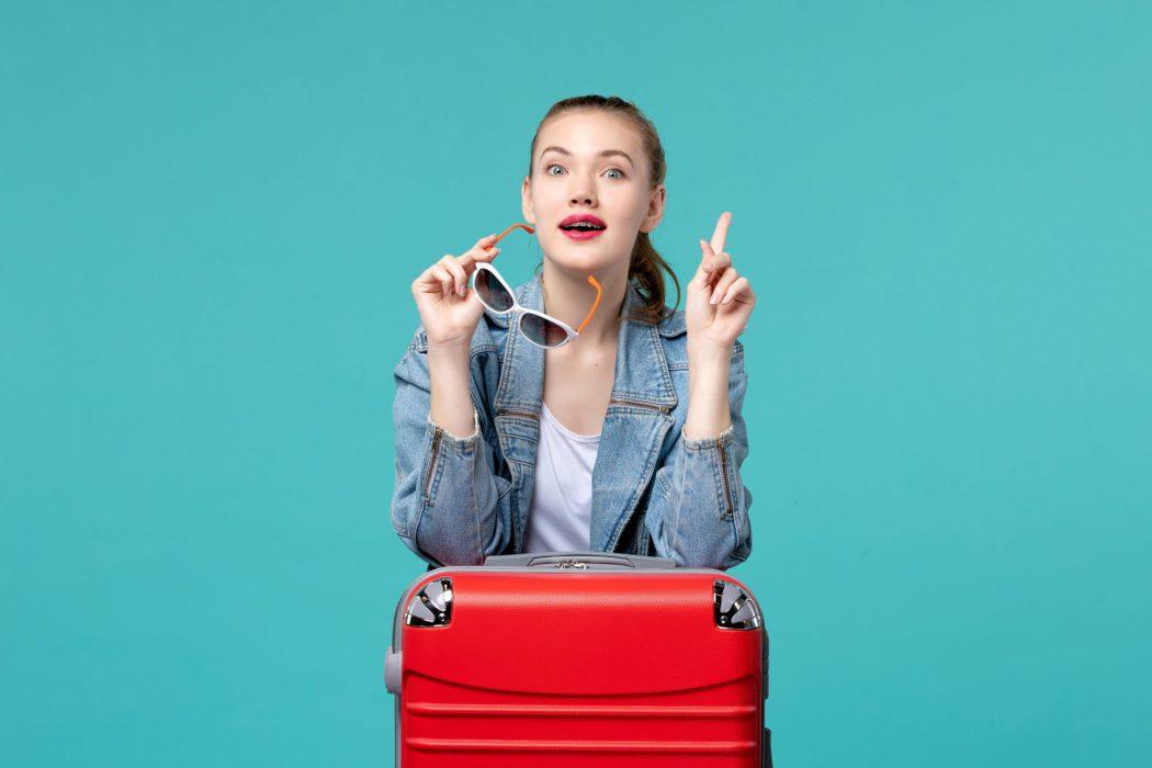 front view young female holding her sunglasses preparing vacation blue desk