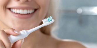 Beautiful woman toothbrush in hand, bathroom setting, electric device, smiling face, personal hygiene, dental care, grooming focus, clean lifestyle, oral health, wellness routine, radiant expression.