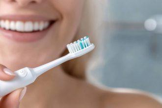 Beautiful woman toothbrush in hand, bathroom setting, electric device, smiling face, personal hygiene, dental care, grooming focus, clean lifestyle, oral health, wellness routine, radiant expression.