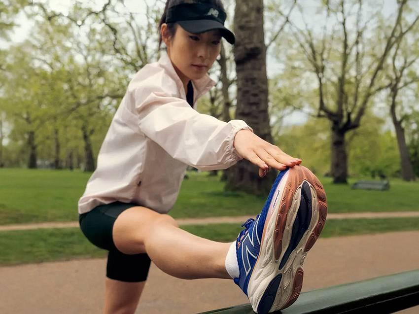 Kobieta w stroju i butach New Balance rozgrzewa się przed bieganiem